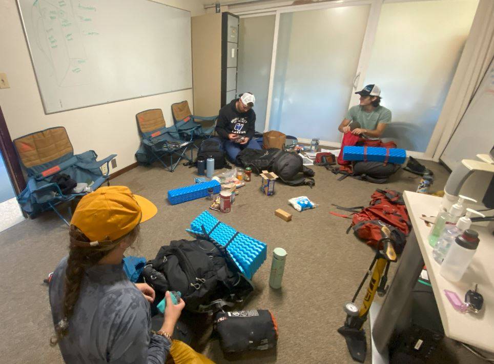 3 students sorting and packing camping gear